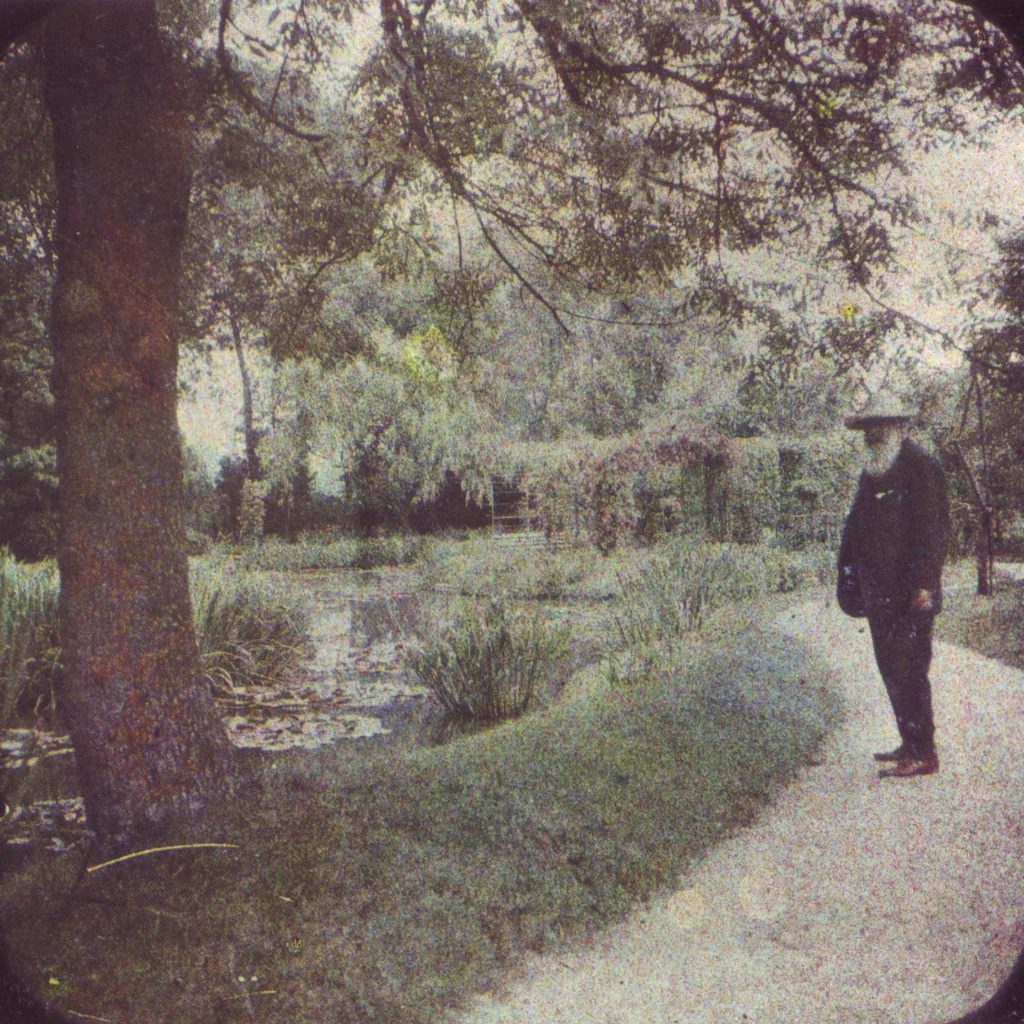 Claude Monet steht neben seinem Seerosenteich in Giverny 